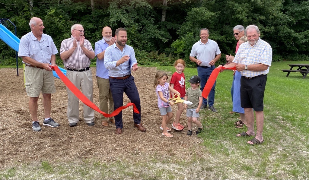 members of council and the community gather to cut the ribbon at the new playground