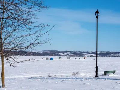 frozen Rice Lake covered in a layer of snow, ice fishing huts are visible in the background