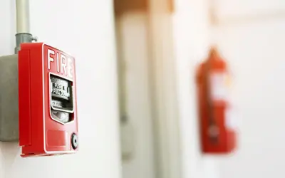 fire alarm in focus with a blurred fire extinguisher in the background