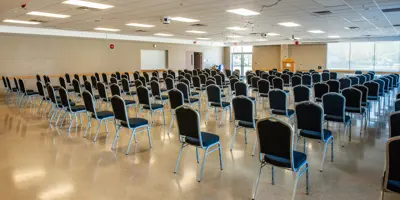 empty banquet hall with chairs arranged in theatre style rows facing a podium