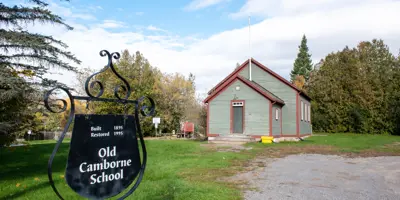 Exterior of Camborne schoolhouse with a sign that reads "Old Camborne School, built 1895, restored 1995"