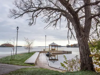 concrete pier with gazebo facing towards Rice Lake with large tree in foreground