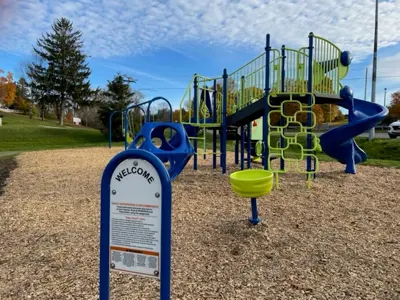 Cold Springs Park focused on a welcome sign with a climbing structure in the background