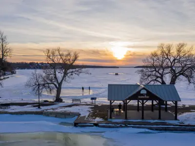 Drone view of a sunset over frozen Rice Lake with two people ice skating in the background