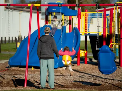 A back view of a person pushing a small child on a swing at the Baltimore arena playground