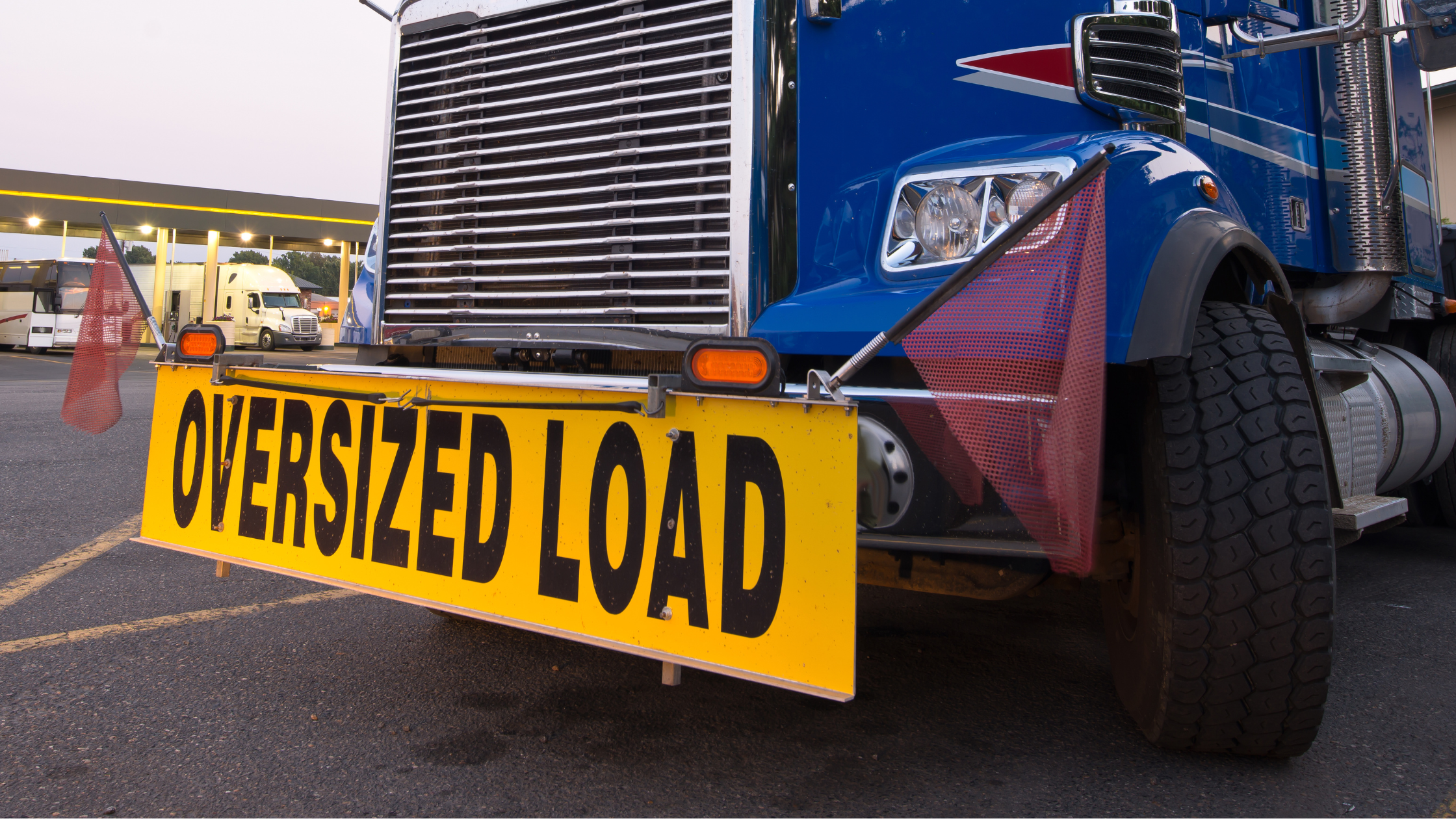 front of transport truck with a large yellow sign reading "oversized load"